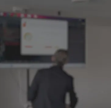 Ponente de espaldas explicando una demo en directo sobre una pantalla grande